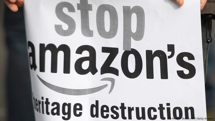 A person holds a placard protesting against Amazon