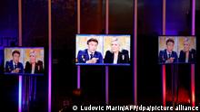 People watch centrist candidate and French President Emmanuel Macron, left, and far-right contender Marine Le Pen during a televised debate at the studios hosting the debate in La Plaine-Saint-Denis, outside Paris, Wednesday, April 20, 2022. In the climax of France's presidential campaign, centrist President Emmanuel Macron and far-right contender Marine Le Pen meet Wednesday evening in a one-on-one television debate that could prove decisive before Sunday's runoff vote. (Ludovic Marin, Pool via AP)