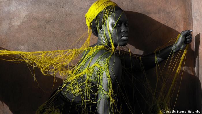 A young woman is covered in yellow yarn