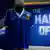 A gloved hand rests on the shoulder of a jersey worn by Diego Maradona, an advertisement wall behind reads 'The Hand of God'