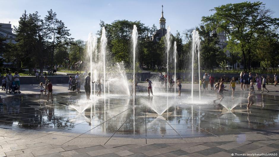 Children play in water fountains in Mariupol