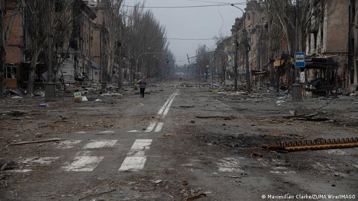 A woman walks along in a destroyed Mariupol street