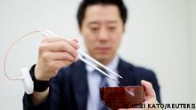 An employee of Kirin Holdings demonstrates chopsticks that can enhance food taste using an electrical stimulation waveform that was jointly developed by the company and Meiji University's School of Science and Technology Professor Homei Miyashita, in Tokyo, Japan April 15, 2022. Picture taken April 15, 2022. REUTERS/Issei Kato