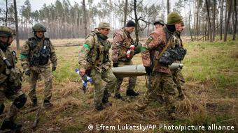 Украинские военные несут фрагмент снаряда РСЗО Ураган в апреле 2022 года