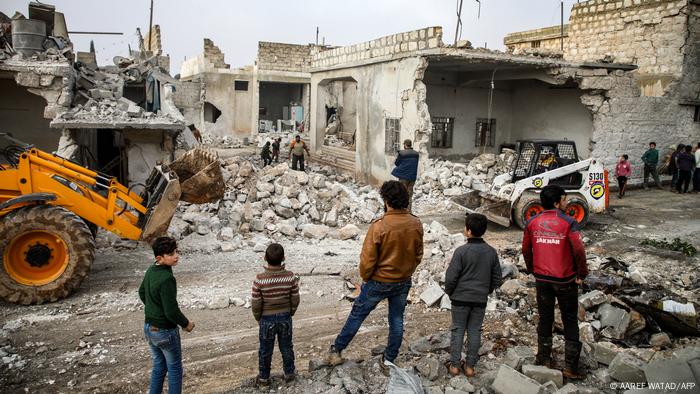 عناصر من الدفاع المدني السوري يستخدمون جرافة لإزالة الأنقاض