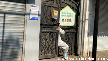 21.4.2022, Shanghai****A person in a protective suit squeezes through a locked gate of a residential compound, following the coronavirus disease (COVID-19) outbreak in Shanghai, China April 21, 2022. REUTERS/Andrew Galbraith TPX IMAGES OF THE DAY 