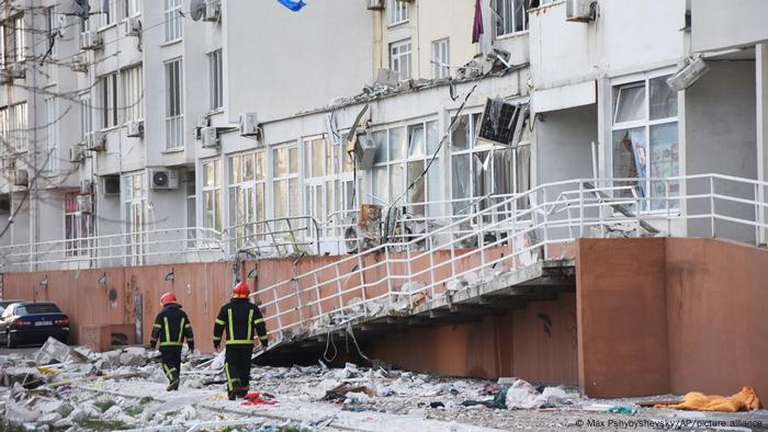 Firefighters walk past an apartment building damaged by Russian shelling in Odesa