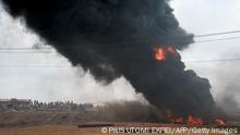 Stranded commuters stand across the road looking at a tanker laden with petrol that is on fire after it fell over and spilt the contents across the Lagos-Ibadan expressway in Magboro, Ogun State, on December 2, 2020. - Economic activities was grounded as traffic was brought to a halt on the Lagos -Ibadan expressway, the busiest inter-state route in Nigeria, after a petrol tanker exploded on the Magboro section after spilling the content across highway. (Photo by PIUS UTOMI EKPEI / AFP) (Photo by PIUS UTOMI EKPEI/AFP via Getty Images)