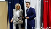 French President Emmanuel Macron, candidate for his re-election, and his wife Brigitte Macron leave the voting booths as they vote for the second round of France's presidential election at a polling station in Le Touquet, northern France, on April 24, 2022. (Photo by GONZALO FUENTES / POOL / AFP)