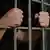 Foto simbólica de unas manos que sostienen las rejas de una cárcel en una imagen de archivo.