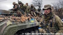 FILE - A Ukrainian serviceman walks next to a fighting vehicle, outside Kyiv, Ukraine, Saturday, April 2, 2022. As he begins a second term as France's president, Emmanuel Macron has given the green light for the delivery of artillery pieces to Ukraine. (AP Photo/Vadim Ghirda, File)