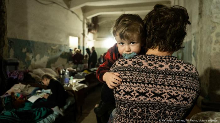 Une femme tient un enfant dans un abri anti-aérien improvisé à Marioupol