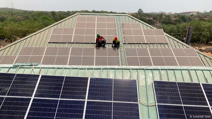 Trabajadores con paneles solares en un tejado en Ghana.