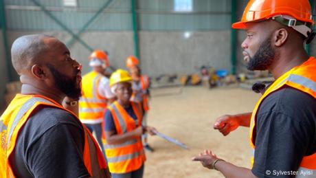 Mehrere Menschen bei einer Planungsbesprechung auf einer Baustelle in Ghana