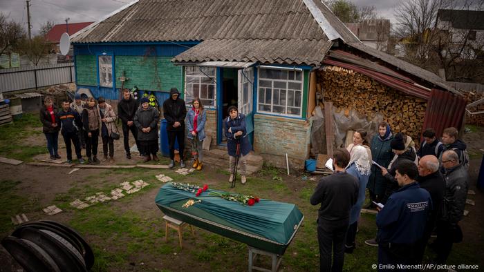 Familiares de una víctima de los ataques rusos en Bucha la sepultan reunidos en el jardín de su casa.