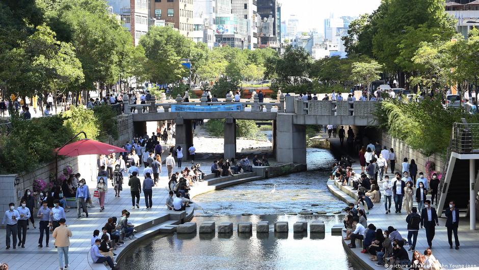 People walk along the banks of the Cheonggye Stream during lunch time in Seoul