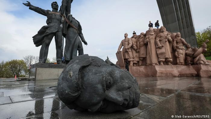 Broken bronze head in front of monument