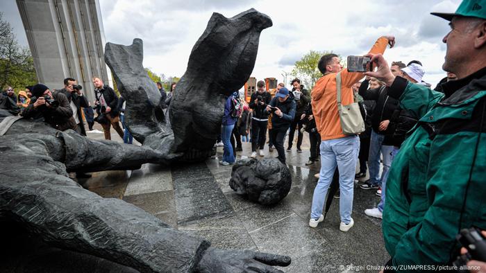 People standing around the dismantled statue