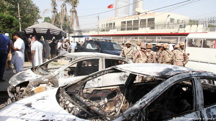 Burned out cars in front of a building with the Chinese flag