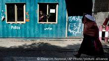 A Taliban fighter stands guard as a woman enters the government passport office, in Kabul, Afghanistan, Wednesday, April 27, 2022. (AP Photo/Ebrahim Noroozi)