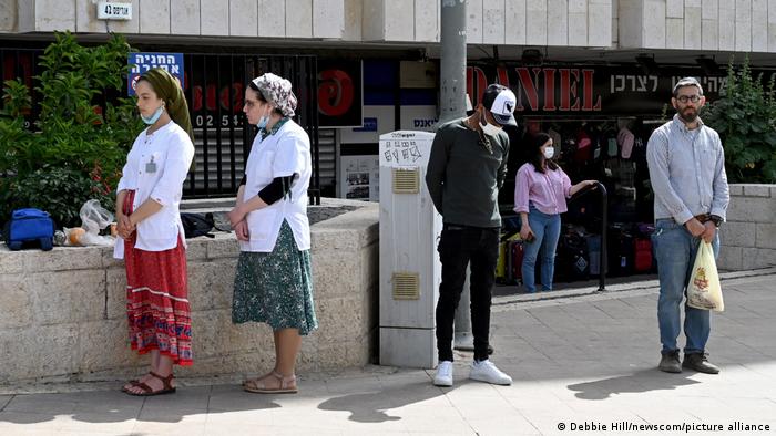 Israelis stand still on a street in Jerusalem during a two-minute siren