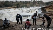 Tourists take pictures on top of the Murchison Falls, one of the majestic natural sites in Africa where the government has a plan to build a hydroelectric dam, on the Victoria Nile at Murchison Falls National Park, northwest Uganda, on January 25, 2020. - The government authorised a consortium led by Bonang Power and Energy to conduct a feasibility study on the construction of a 360-megawatt dam on the Uhuru Falls adjacent to the Murchison falls in Murchison National Park which is also the second most visited park in Uganda, after Queen Elizabeth National Park. (Photo by Yasuyoshi CHIBA / AFP) (Photo by YASUYOSHI CHIBA/AFP via Getty Images)