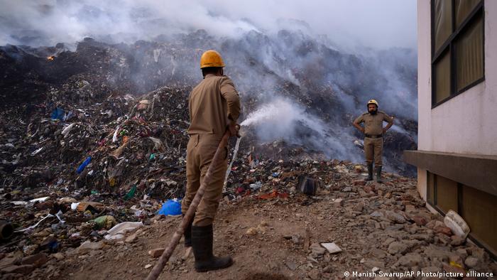 Neu-Delhi: Zwei Feuerwehrleute versuchen einen brennenden Müllberg zu löschen