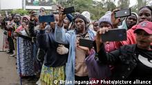 Members of the public take photographs with their smartphones during the procession at the state funeral of Kenya's former President Mwai Kibaki, in the capital Nairobi, Kenya Friday, April 29, 2022. Kenyans are paying their last respects to the former leader, whose death was announced last Friday, in a state funeral service that is attended by African leaders. (AP Photo/Brian Inganga)