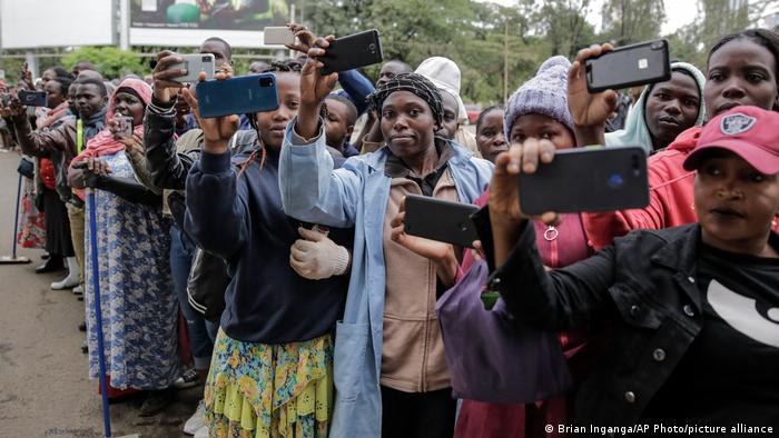 Members of the public take photographs with their smartphones during the procession at the state funeral of Kenya's former President Mwai Kibaki, in the capital Nairobi, Kenya Friday, April 29, 2022.