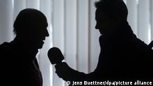 A man is interviewed by a radio journalist after a press conference in Schwerin, Germany, 25 November 2014. Photo: Jens Buettner