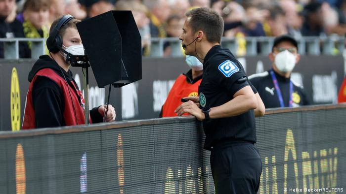 Bundesliga-Schiedsrichter Robert Hartmann betrachtet strittige Spielszene auf Monitor am Spielfeldrand