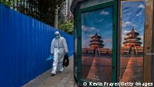 BEIJING, CHINA - APRIL 29: A health worker wears protective closing as he walks with disinfectant equipment along the fence of a community in lockdown due to a local COVID-19 outbreak on April 29, 2022 in Beijing, China. China is trying to contain a spike in coronavirus cases in capital Beijing, after dozens of people tested positive for the virus in recent days. Local authorities have initiated mass testing in most districts and locked down some neighbourhoods where cases are found in an effort to maintain the country's zero COVID strategy. (Photo by Kevin Frayer/Getty Images)