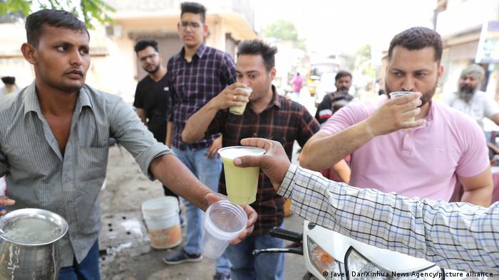 A vendor serves cold sugarcane juice to customers