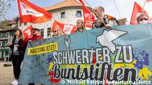 Menschen beim Demonstrationszug des DGB tragen ein Plakat mit der Aufschrift „Schwerter zu Buntstiften“. Maikundgebungen des Deutschen Gewerkschaftsbundes (DGB) finden in zahlreichen Städten des Freistaats statt.