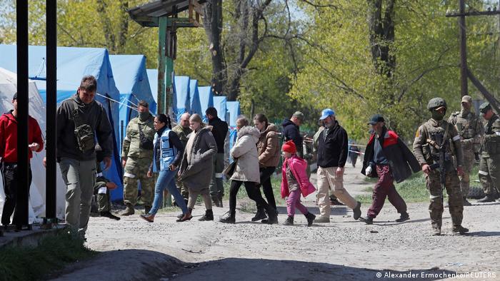 Civilians who left the area near Azovstal steel plant in Mariupol walk accompanied by UN staff at a temporary accommodation center