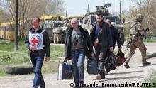 Civilians who left the area near Azovstal steel plant in Mariupol walk accompanied by a member of the International Committee of the Red Cross (ICRC) at a temporary accommodation centre during Ukraine-Russia conflict in the village of Bezimenne in the Donetsk Region, Ukraine May 1, 2022. REUTERS/Alexander Ermochenko