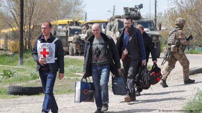 Civilians who left the area near Azovstal steel plant in Mariupol walk accompanied by a member of the International Committee of the Red Cross (ICRC) at a temporary accommodation center