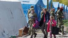 Civilians who left the area near Azovstal steel plant in Mariupol walk accompanied by a service member of pro-Russian troops at a temporary accommodation centre during Ukraine-Russia conflict in the village of Bezimenne in the Donetsk Region, Ukraine May 1, 2022. REUTERS/Alexander Ermochenko