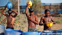 Workers use their helmets to pour water to cool themselves in Ahmedabad, India