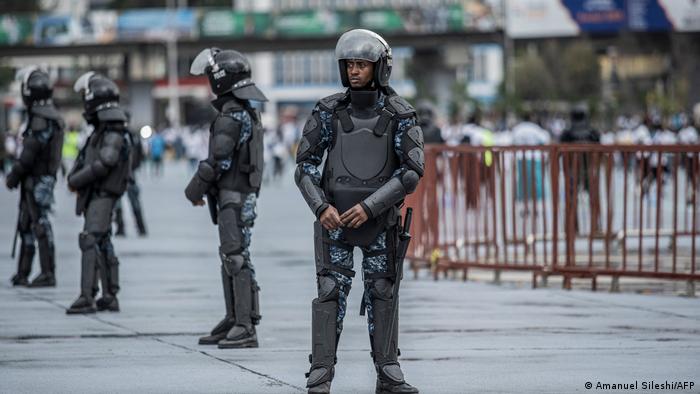 Armed police officers wearing riot gear stand guard