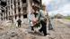 Women walk past a destroyed apartment building in Mariupol, Ukraine Women walk past a destroyed apartment building in Mariupol, Ukraine