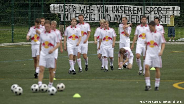 A protest poster with the inscription Hands off our sport! In Leipzig and everywhere hangs behind the players of RB Leipzig during training.