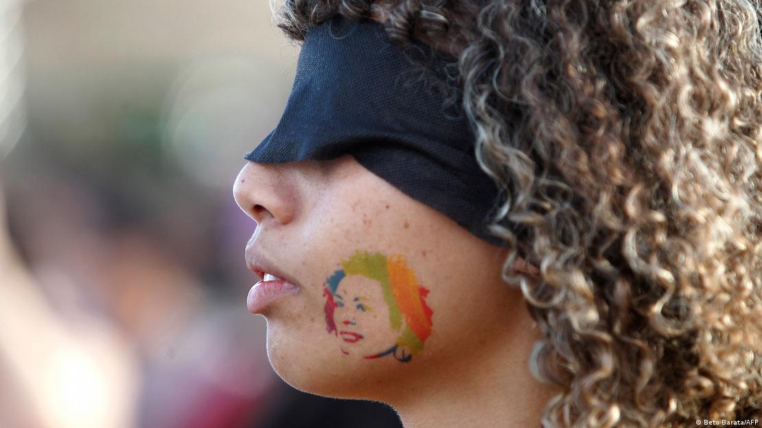 Mulher com venda nos olhos e tatuagem de Marielle Franco no rosto