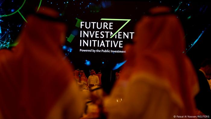 Participants look at a sign of the Future Investment Initiative during the investment conference in Riyadh, Saudi Arabia.