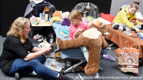 Жінка із Запоріжжя з двома дітьми у пункті прийому українських біженців в одному зі спортзалів у німецькому місті Біттерфельд