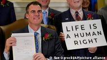 Oklahoma Gov. Kevin Stitt poses for a photo with the bill he signed, making it a felony to perform an abortion, punishable by up to 10 years in prison, Tuesday, April 12, 2022, in Oklahoma City, following a bill signing ceremony. (AP Photo/Sue Ogrocki)
