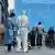 Workers in protective suits stand by a line of citizens waiting to be tested in Beijing