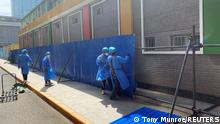 Workers in protective clothing erect barricades outside a residential building under lockdown in Chaoyang district, amid the coronavirus disease (COVID-19) outbreak in Beijing, China May 4, 2022. REUTERS/Tony Munroe