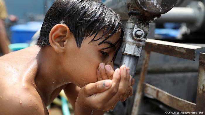 Boy drinking water from a municipal tanker in Delhi, India