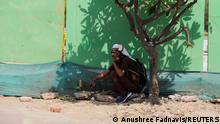 A man takes shelter under a tree on a hot summer day, in New Delhi, India, April 27, 2022. REUTERS/Anushree Fadnavis